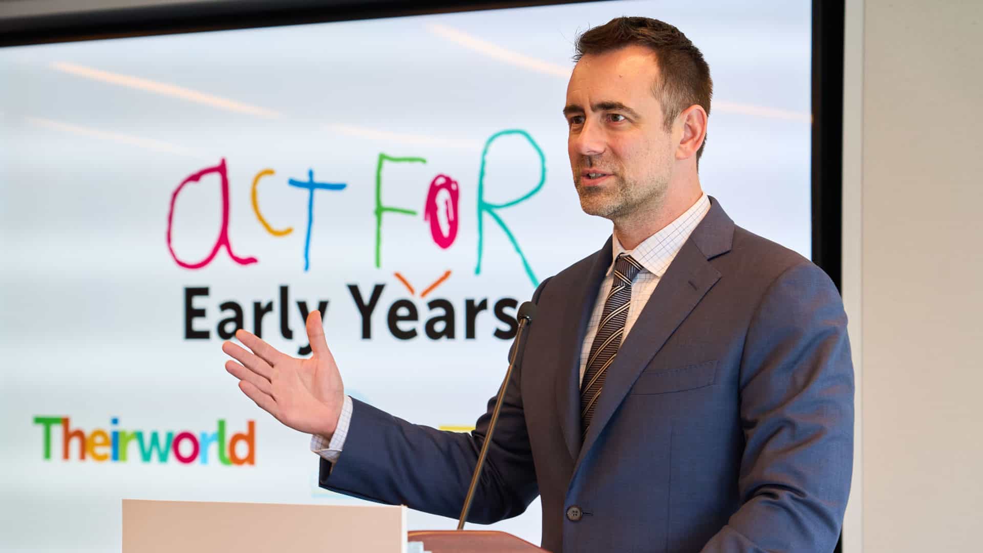 A man in a suit giving a speech at a podium.