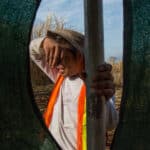 A man is looking through a hole in a fence.
