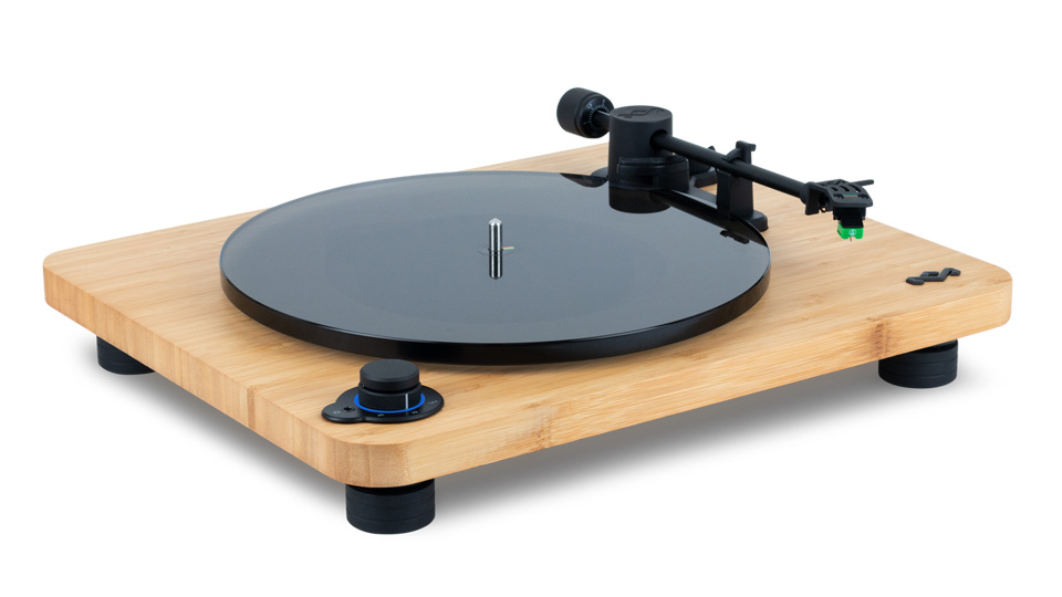 A sleek turntable with a bamboo base, a black platter, and a tonearm mounted on the right side. The turntable has a minimalist design with a central spindle for placing vinyl records. Three round feet support the base, making it an essential addition to any audiophile's directory of must-have gadgets.